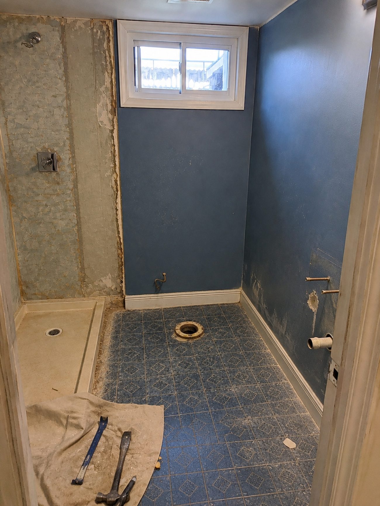 Basement bathroom shower panels stripped and toilet removed during demolition in Baltimore County