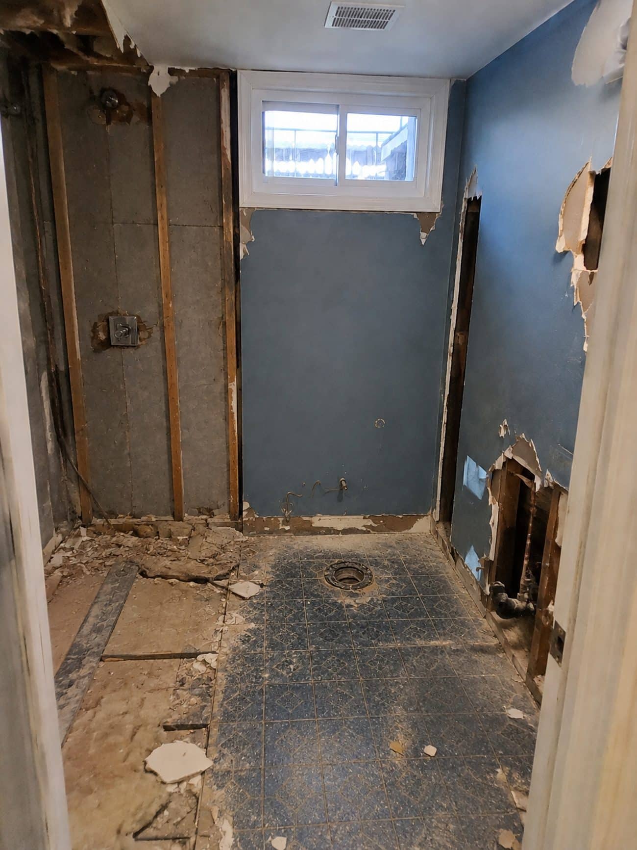 Basement bathroom walls opened during demolition exposing framing and old plumbing