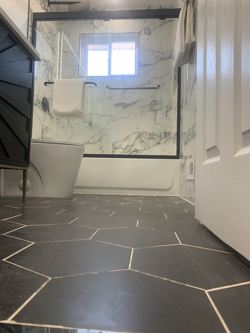 Finished full bathroom floor tile with black framed shower glass