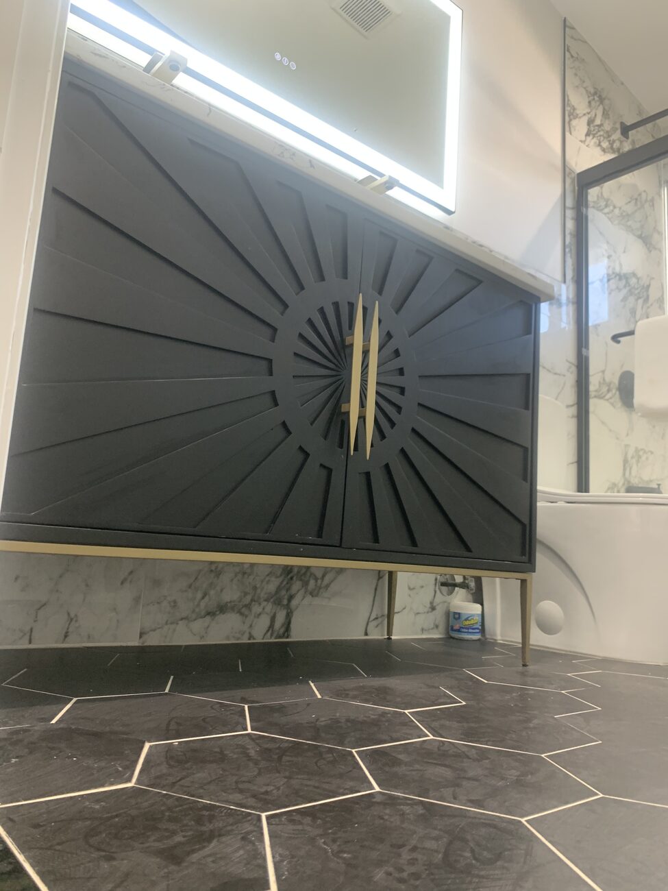 Close-up of a navy vanity with gold sunburst detail in a finished Baltimore County bathroom