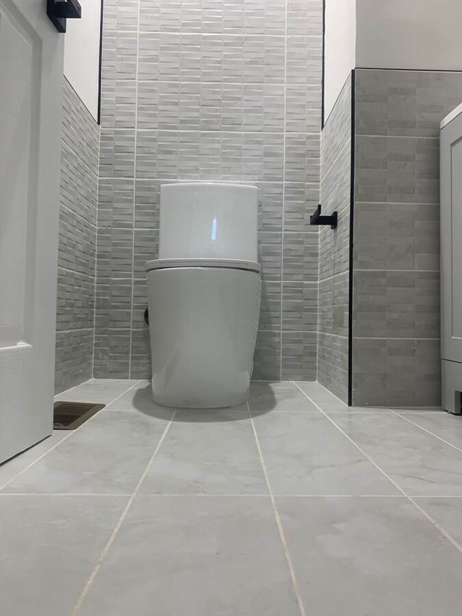 Finished powder room with gray stacked tile and matte black fixtures