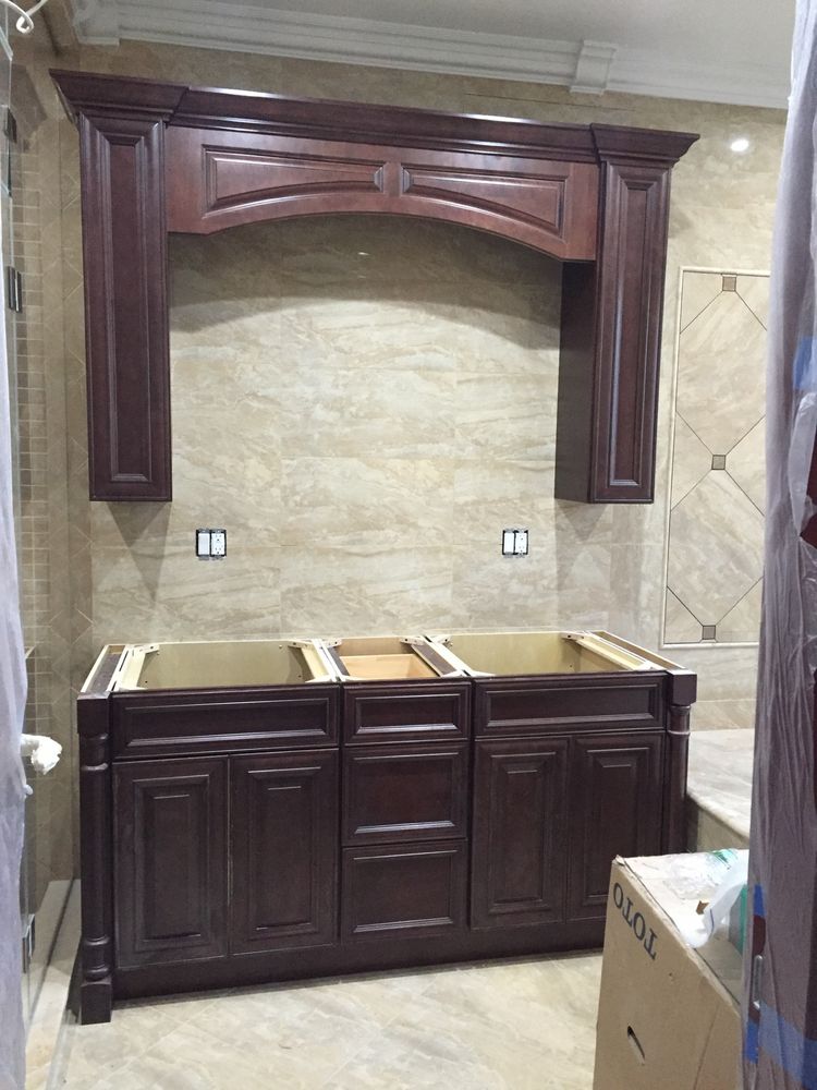 Arched cherry valance and mirrored medicine cabinets above a double vanity mid-installation